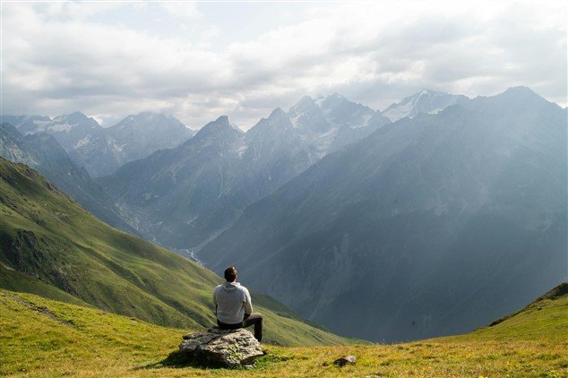Personne assise sur un rocher face à la montagne, illustrant un moment de réflexion sur son parcours professionnel