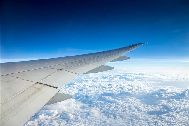Vue depuis un hublot d’avion, aile en plein ciel au-dessus des nuages –métaphore d’un nouveau départ après un travail toxique