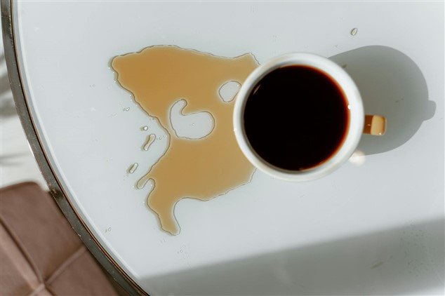 Tasse de café sur une table, partiellement renversée : image symbolique d’un moment qui dérape, comme un mot mal placé en entretien