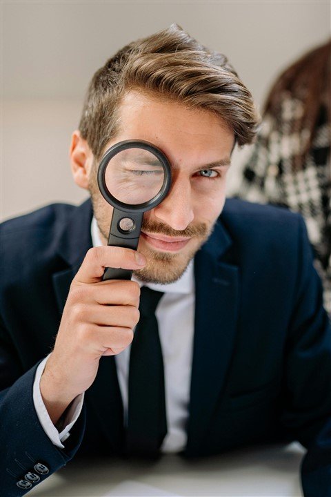 Recruteur en costume tenant une loupe, représentant l’attention portée aux moindres détails lors d’un entretien d’embauche