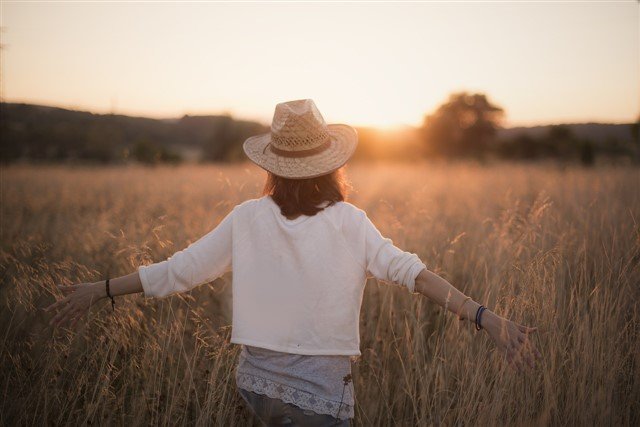Femme de dos avançant dans un champ vers le soleil couchant, symbolisant l’espoir et la sortie d’un poste avec un manager toxique.