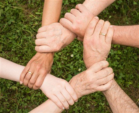 Mains de collaborateurs formant une chaîne de solidarité, symbolisant le soutien en équipe et les alliances face à un manager toxique.