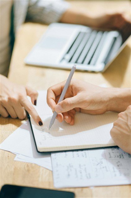 Personne qui aide son collègue, pour illustrer qu'elle devient la personne vers qui on se tourne, signe que sa carrière progresse.