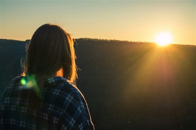 Femme regardant un coucher de soleil, métaphore des perspectives de carrière même lorsqu'on pense que l'on stagne
