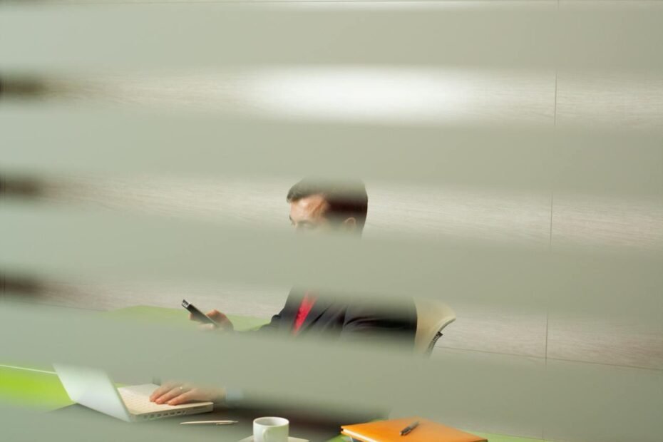 Scène de bureau vue à travers des stores, pouvant évoquer le sentiment : "une collègue me surveille au travail"