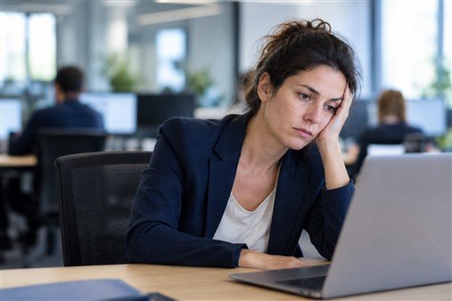 Cadre pensive à son bureau, tendue face à un travail qu'elle n'apprécie plus